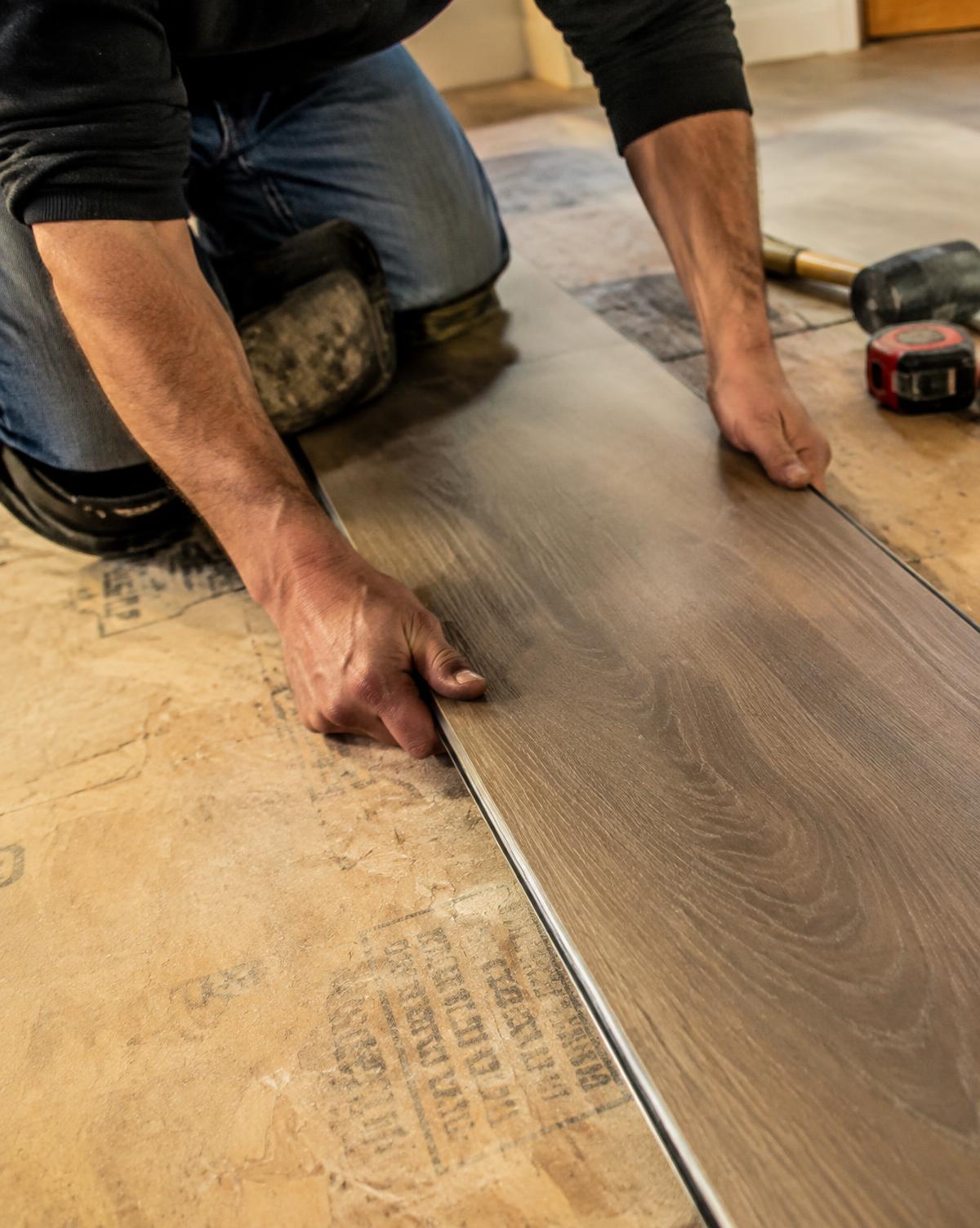 Installer laying a vinyl plank board over a prepared subfloor